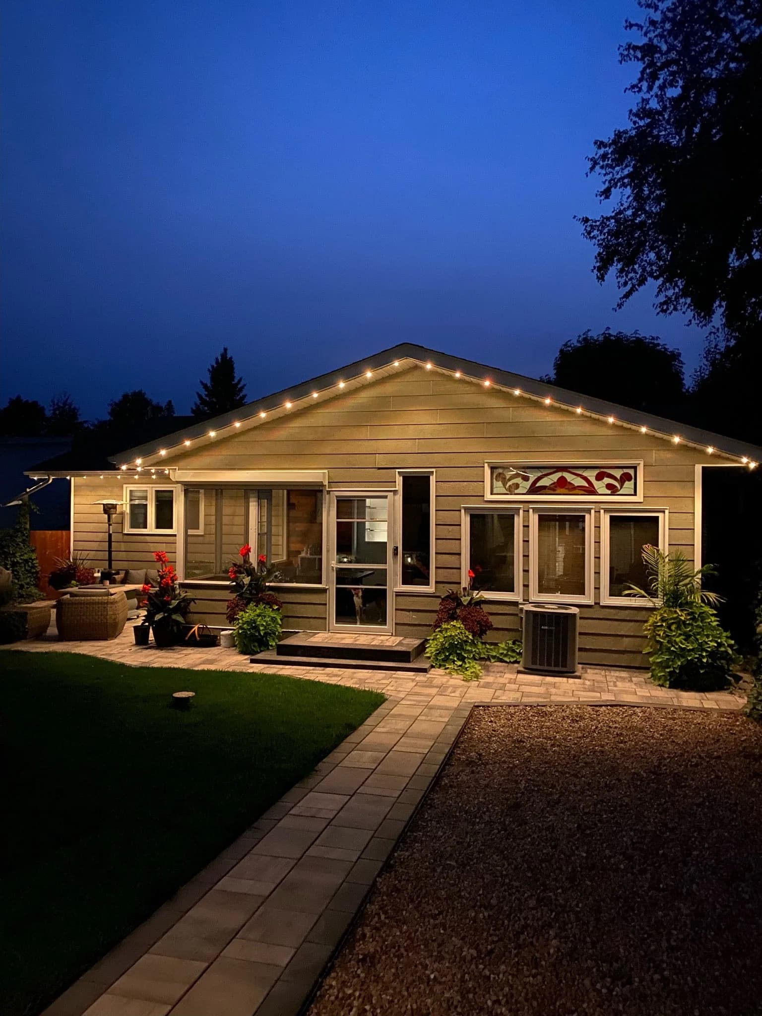 Cottage eaves lit with warm permanent LED lighting at dusk