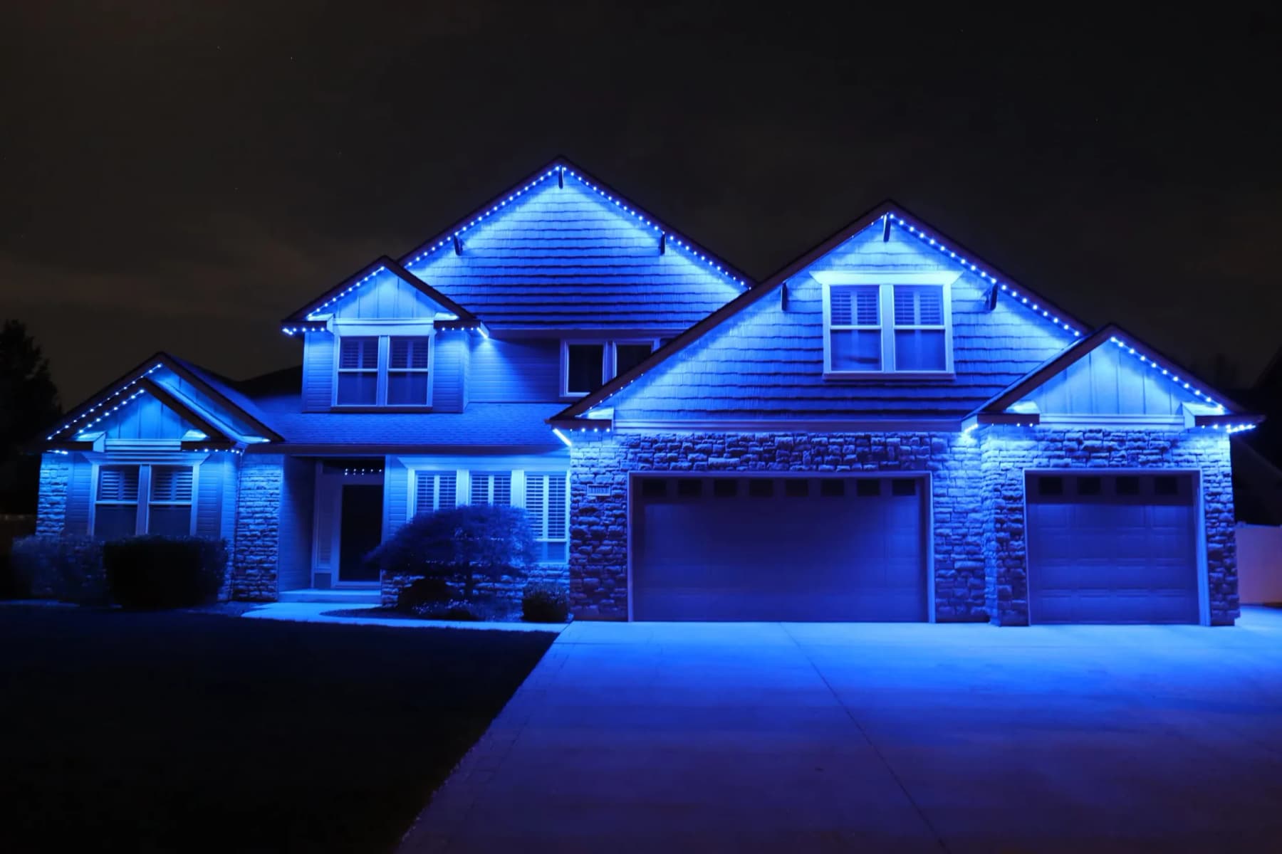 Two-storey home fully outlined at night by soffit-mounted LED track lighting