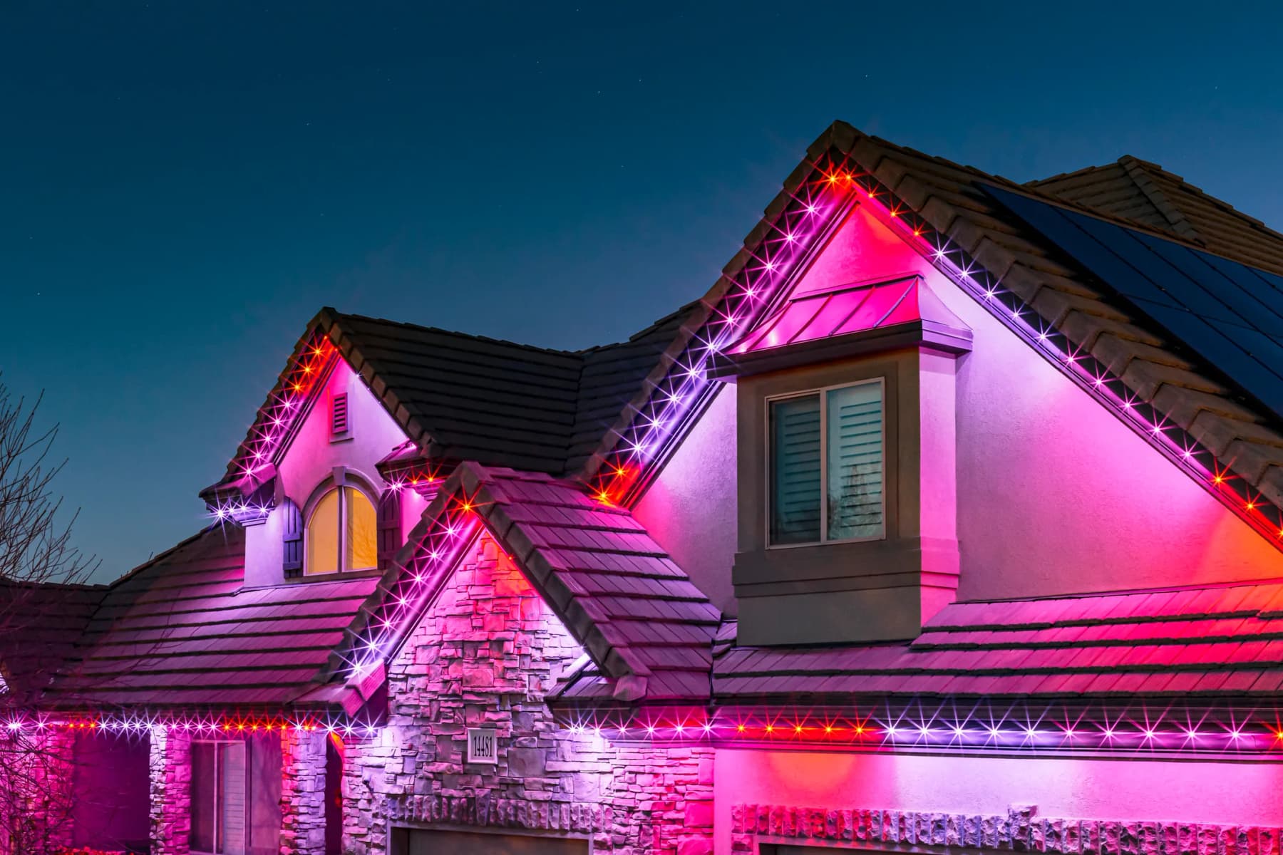 Home exterior lit with warm LED track lighting along the roofline and garage